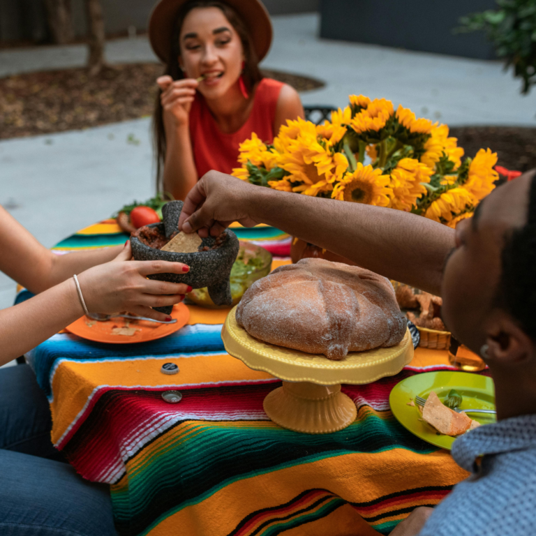 Ludzie jedzący w meksykańskiej knajpie - pełne talerze, uśmiechy i rozmowy, atmosfera pełna ciepła i wspólnego dzielenia się posiłkiem.